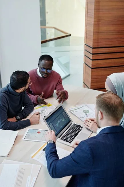 Two adults in an office discussing marketing strategy around a round table.